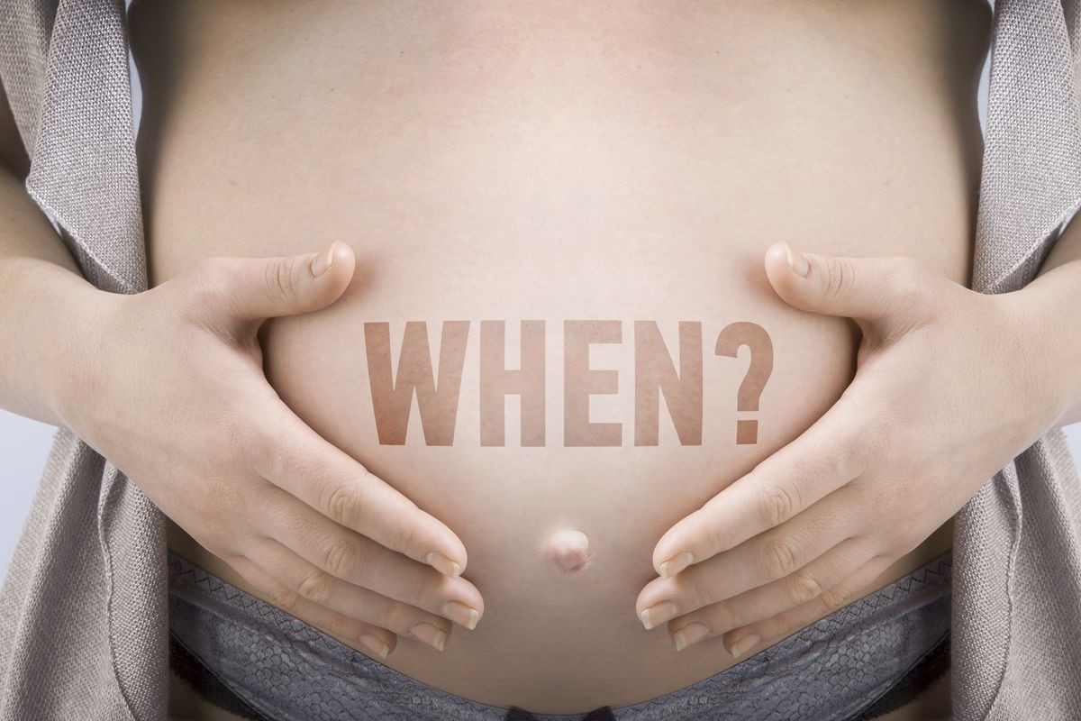 Pregnant woman supports her belly with an inscription "When?"